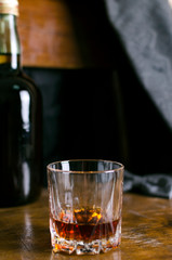 Vertical shot of old-fashioned glass of rum on the vintage wooden chair