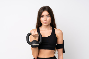 Fototapeta premium Young sport woman over isolated white background making weightlifting with kettlebell and looking to the front