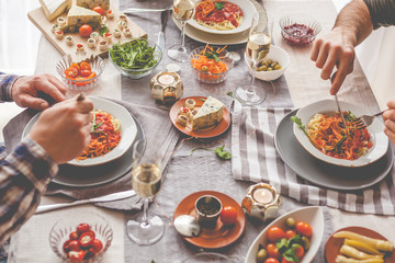 High angle view of dining table full of food with unrecognizable people.