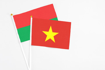 Vietnam and Burkina Faso stick flags on white background. High quality fabric, miniature national flag. Peaceful global concept.White floor for copy space.