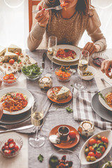 Unrecognizable woman eating lunch at dining table full of food.