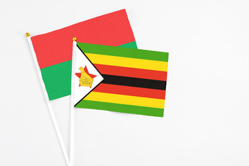 Zimbabwe and Burkina Faso stick flags on white background. High quality fabric, miniature national flag. Peaceful global concept.White floor for copy space.