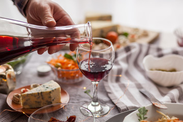Close up of unrecognizable man pouring wine during lunch at dining table.