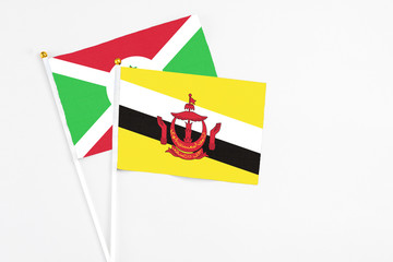 Brunei and Burundi stick flags on white background. High quality fabric, miniature national flag. Peaceful global concept.White floor for copy space.