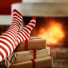 Woman legs with christmas woolen socks and home interior with fireplace.Free space for your decoration and xmas december cold night.