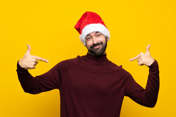 Man with christmas hat over isolated yellow background proud and self-satisfied