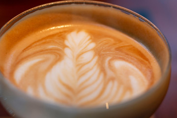 Latte art at cafe or Coffee shop. Cup of art latte on a cappuccino coffee. Cappuccino with frothy foam, coffee cup top view closeup. Coffee late art.