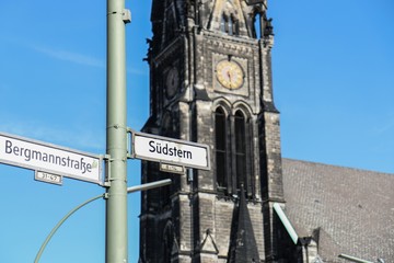 Street Signs of Südstern and Hasenheide with gothic church in background on a clear sunny day