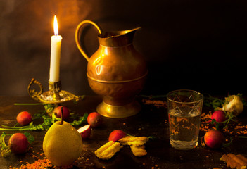 Pear and glass of water with candle on dark table. Still life