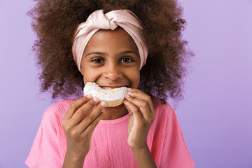 Optimistic young african girl eat donut.