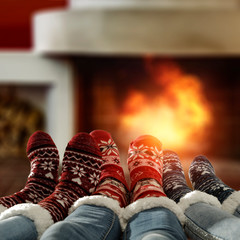 Woman legs with christmas woolen socks and home interior with fireplace.Free space for your...