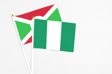 Nigeria and Burundi stick flags on white background. High quality fabric, miniature national flag. Peaceful global concept.White floor for copy space.