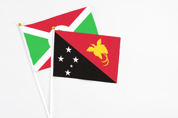 Papua New Guinea and Burundi stick flags on white background. High quality fabric, miniature national flag. Peaceful global concept.White floor for copy space.