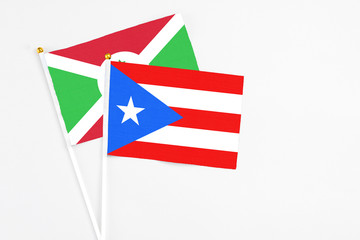 Fototapeta premium Puerto Rico and Burundi stick flags on white background. High quality fabric, miniature national flag. Peaceful global concept.White floor for copy space.