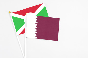 Qatar and Burundi stick flags on white background. High quality fabric, miniature national flag. Peaceful global concept.White floor for copy space.