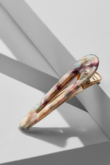 Object shot of a golden alligator hair clip with narrow mother-of-pearl overlay. The pin is in a...