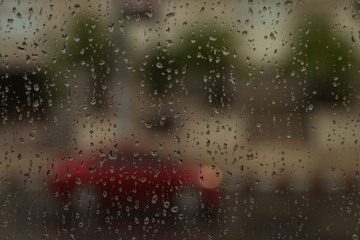 Rain on a window looking out there are cars on the road.