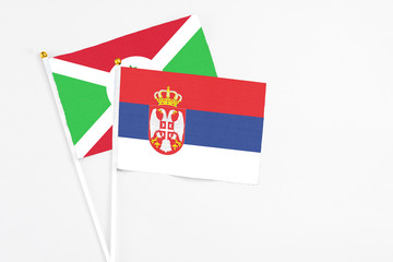 Serbia and Burundi stick flags on white background. High quality fabric, miniature national flag. Peaceful global concept.White floor for copy space.