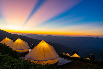 Camping and white tent on the hill with crepuscular rays after sunset background, Chiangrai Thailand