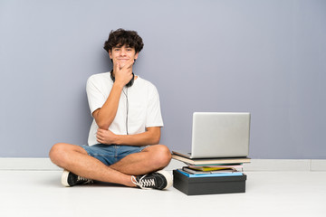 Young man with his laptop sitting one the floor laughing