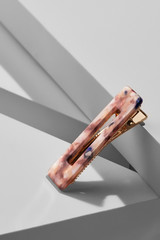 Object shot of a golden alligator hair clip with mother-of-pearl overlay. The pin is in a vertical...