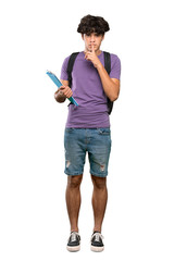A full-length shot of a Young student man showing a sign of silence gesture putting finger in mouth over isolated white background