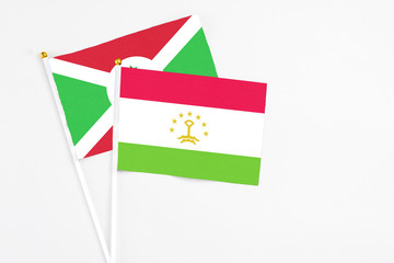 Tajikistan and Burundi stick flags on white background. High quality fabric, miniature national flag. Peaceful global concept.White floor for copy space.