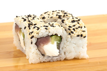 Sushi maki rolls with sesame and tuna on a wooden board.