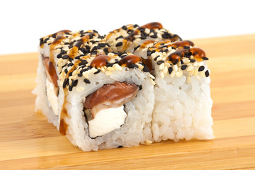 Sushi maki rolls with sesame and tuna on a wooden board.