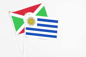 Uruguay and Burundi stick flags on white background. High quality fabric, miniature national flag. Peaceful global concept.White floor for copy space.