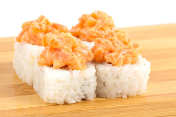 Sushi maki rolls with spicy tuna on a wooden board.