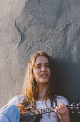 Young woman playing ukulele on the street