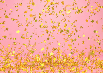 Golden confetti falling on pink background