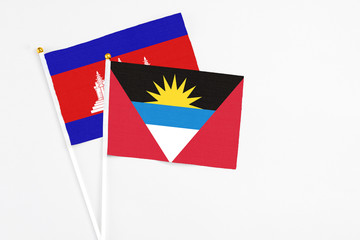 Antigua and Barbuda and Cambodia stick flags on white background. High quality fabric, miniature national flag. Peaceful global concept.White floor for copy space.