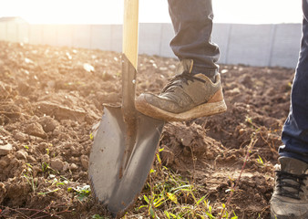 The man is digging the soil ground on his country house