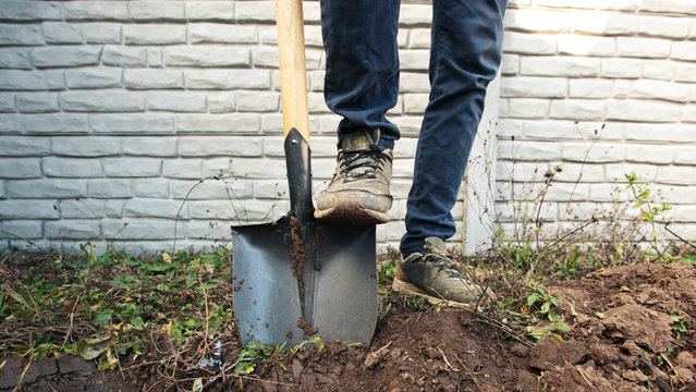 The man is digging the soil ground on his country house