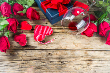 Valentines Day background with handmade red textile hearts,red ribbon, wine glass and roses. Rustic wooden background  top view copy space