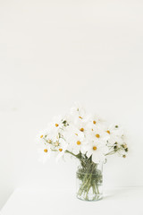 A beautiful background with white chamomile, daisy flowers in vase standing on white table.  Holiday, wedding, birthday, anniversary concept.