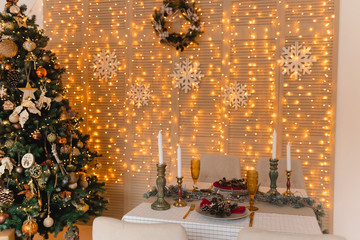 Served table with christmas decor and christmas tree and bokeh lights background, new year celebration concept. 