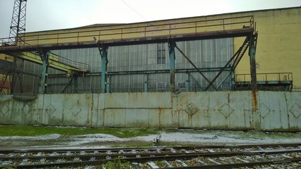 Building of the destroyed abandoned factory. Old workshop. Rusty metal structures and dirty fence with corrosion and damaged texture. Devastation, economy, finance, industry, technology crisis concept