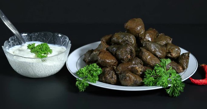 Fresh sarmale, Romanian and Moldovan typical food. Grape vines leaves stuffed with meat, rice and vegetables with sour cream. Sarmale, dolma, sarma, golubtsy or golabki with cheese pies and sour cream