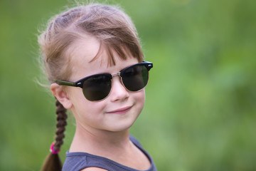 Portrait of pretty child girl with braids in hair outdoors in summer.