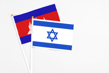 Obraz premium Israel and Cambodia stick flags on white background. High quality fabric, miniature national flag. Peaceful global concept.White floor for copy space.