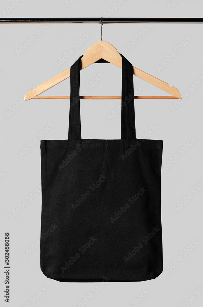 Wall mural black tote bag mockup hanging on a clothes hanger.