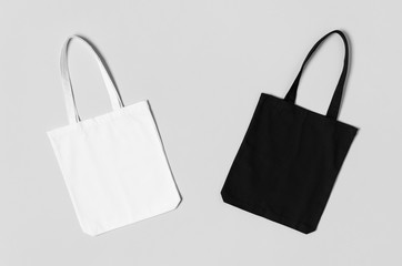 White and black tote bags mockup on a grey background.