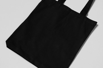 Black tote bag mockup on a grey background.
