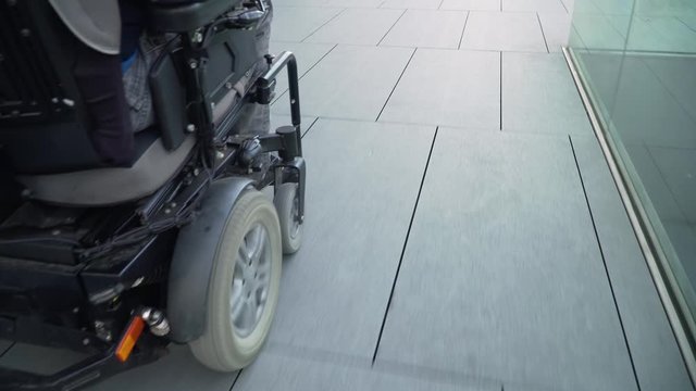 4k resolution closeup follow from a back of a man on electric wheelchair driving on a street. Accessibility concept