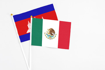 Mexico and Cambodia stick flags on white background. High quality fabric, miniature national flag. Peaceful global concept.White floor for copy space.