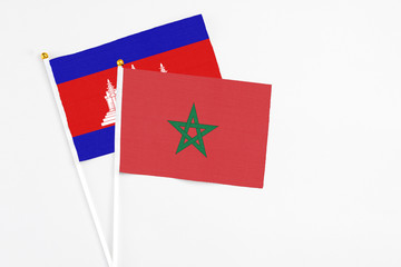 Morocco and Cambodia stick flags on white background. High quality fabric, miniature national flag. Peaceful global concept.White floor for copy space.