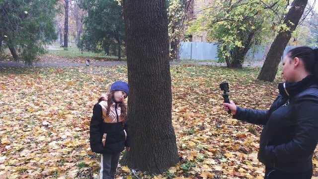 Woman photographs girl in autumn park